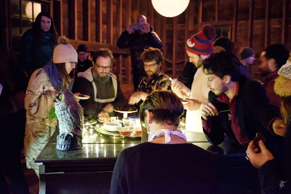 A group preparing food together in a wooden hall