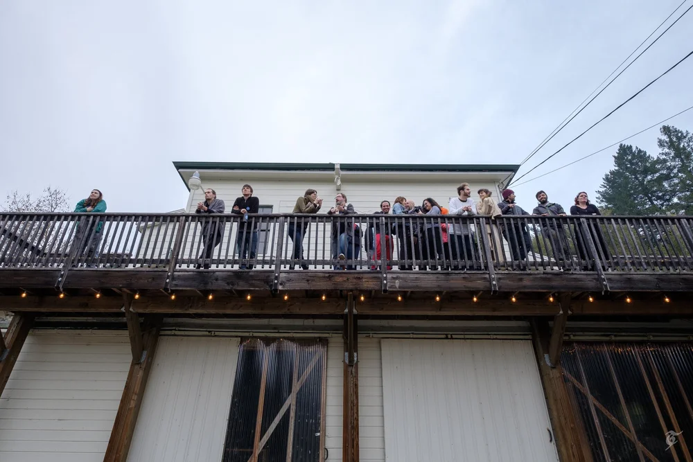 Participants waving from a farmhouse balcony
