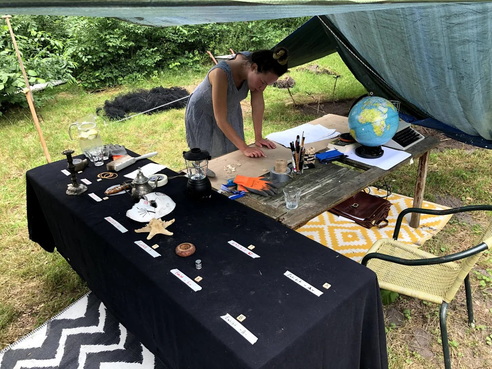 A participant crafting at a table full of maps and props