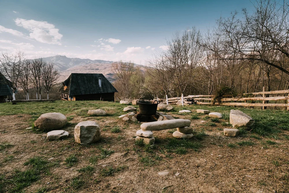 Wooden houses and a fire pit on a hillside